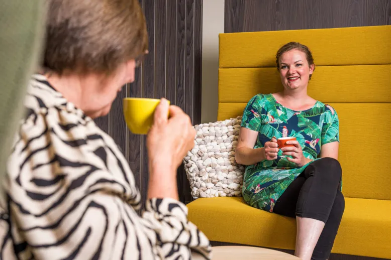 Psycholoog en verpleegkundig specialist in gesprek terwijl zij een kop koffie of thee vasthouden