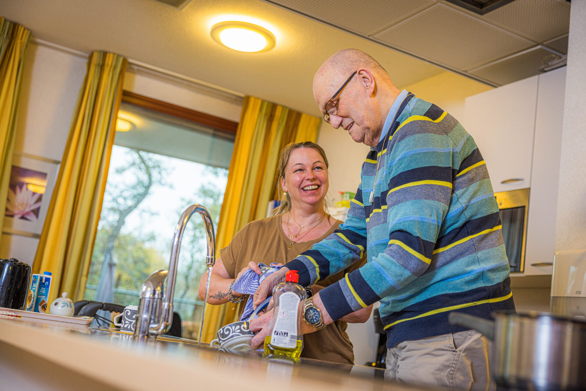 Zorgmedewerker helpt bewoner bij het doen van de vaat