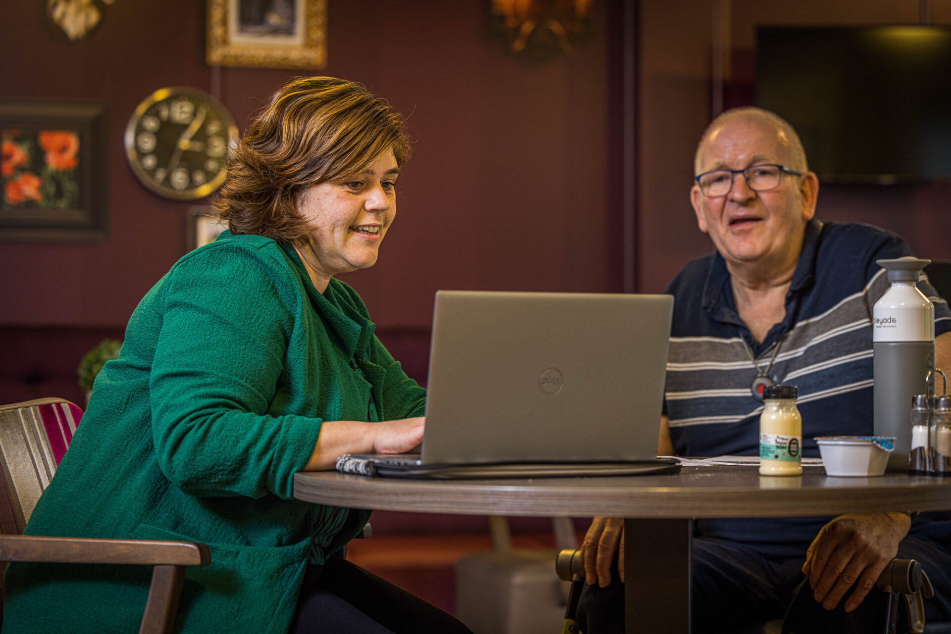 Vrijwilliger kijkt samen met een bewoner naar een laptop
