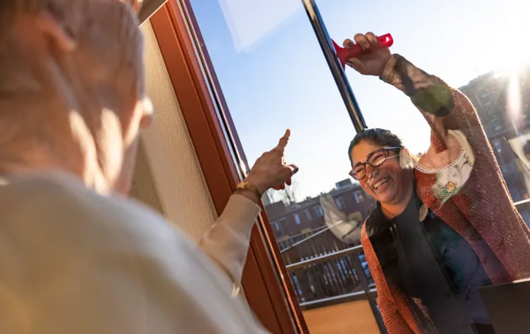 Thuiszorg medewerker zeemt vrolijk de ramen