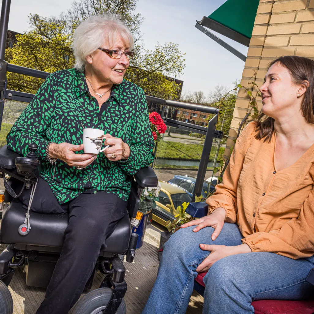 Vrijwilliger in gesprek met bewoner op balkon