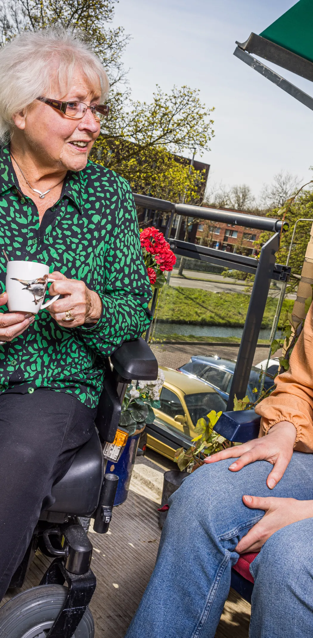 Vrijwilliger in gesprek met bewoner op balkon