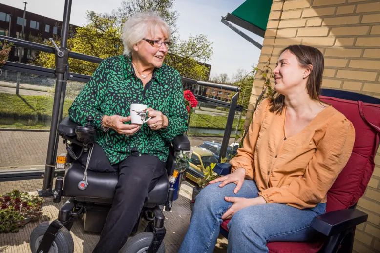 Vrijwilliger in gesprek met bewoner op balkon