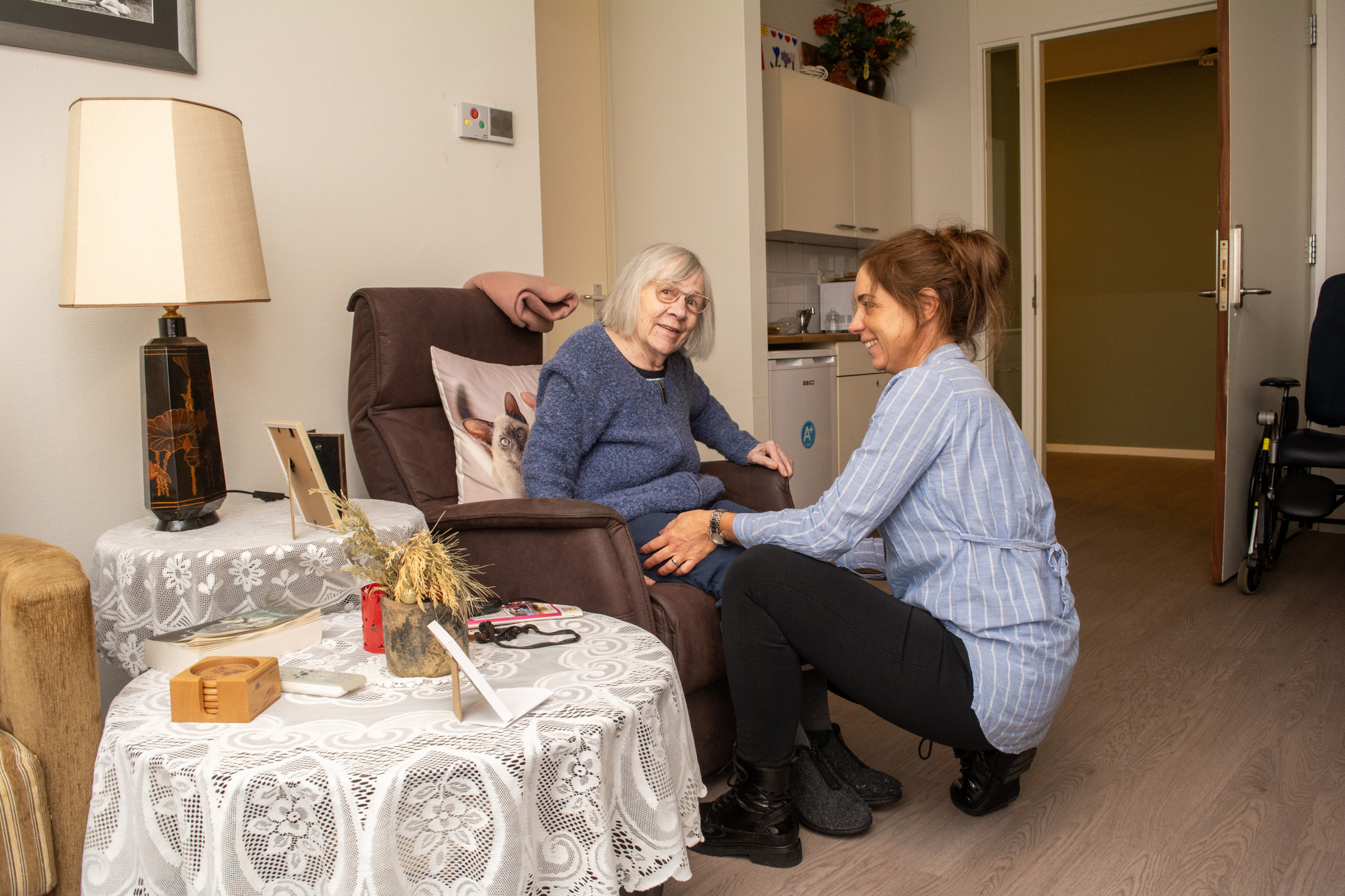 Medewerker helpt bewoner uit de stoel