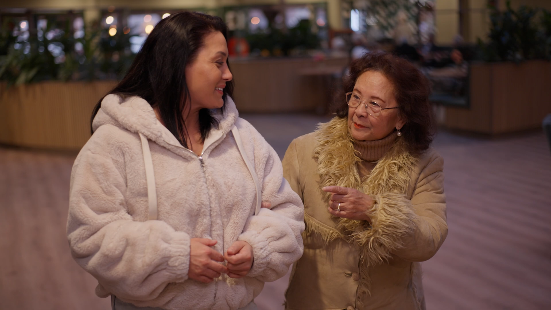Twee dames in beeld lopend door een Pleyade-locatie. Klaar voor een wandeling buiten. De zorg van morgen, doen we samen.